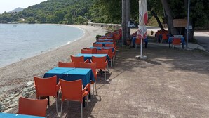 Ein Restaurant direkt am Strand mit Terrassenplätzen, inklusive Tische und Stühle.