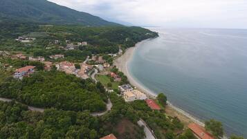 An aerial view of a coastal town with a beach, houses, and greenery.
