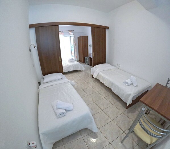 Una habitación con dos camas individuales, un escritorio de madera y una silla.