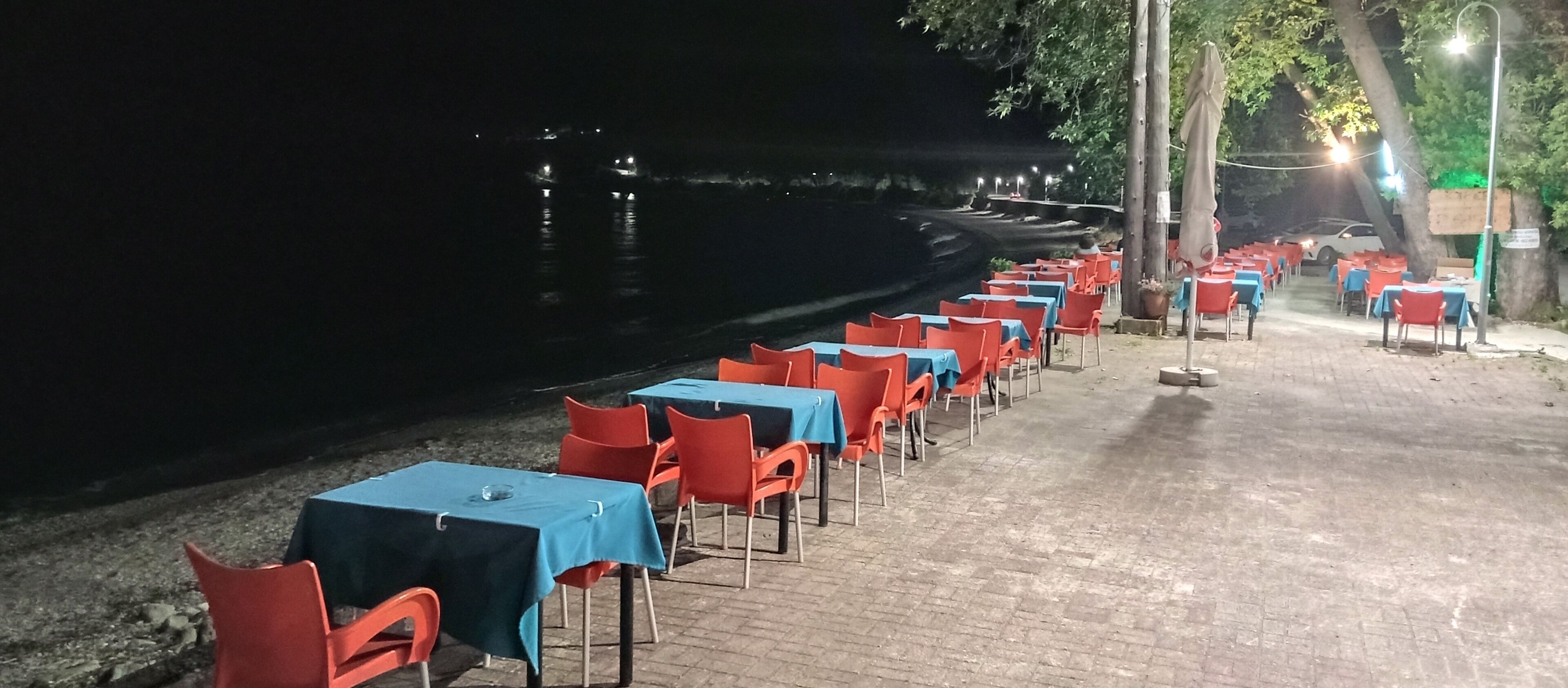 Un área de comedor a la orilla del río, con mesas y sillas dispuestas junto al agua.