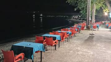 Un área de comedor a la orilla del río, con mesas y sillas dispuestas junto al agua.