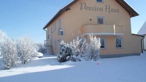 A two-story building with the name "Pension Haas" on the facade, surrounded by snow-covered trees and a clear sky. - Pension Haas- Hotel am Turm (Rottweil)