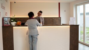 A reception area with a modern design, featuring a reception desk, a potted plant, and a wall with 'Welcome' text. - Pension Haas- Hotel am Turm (Rottweil)