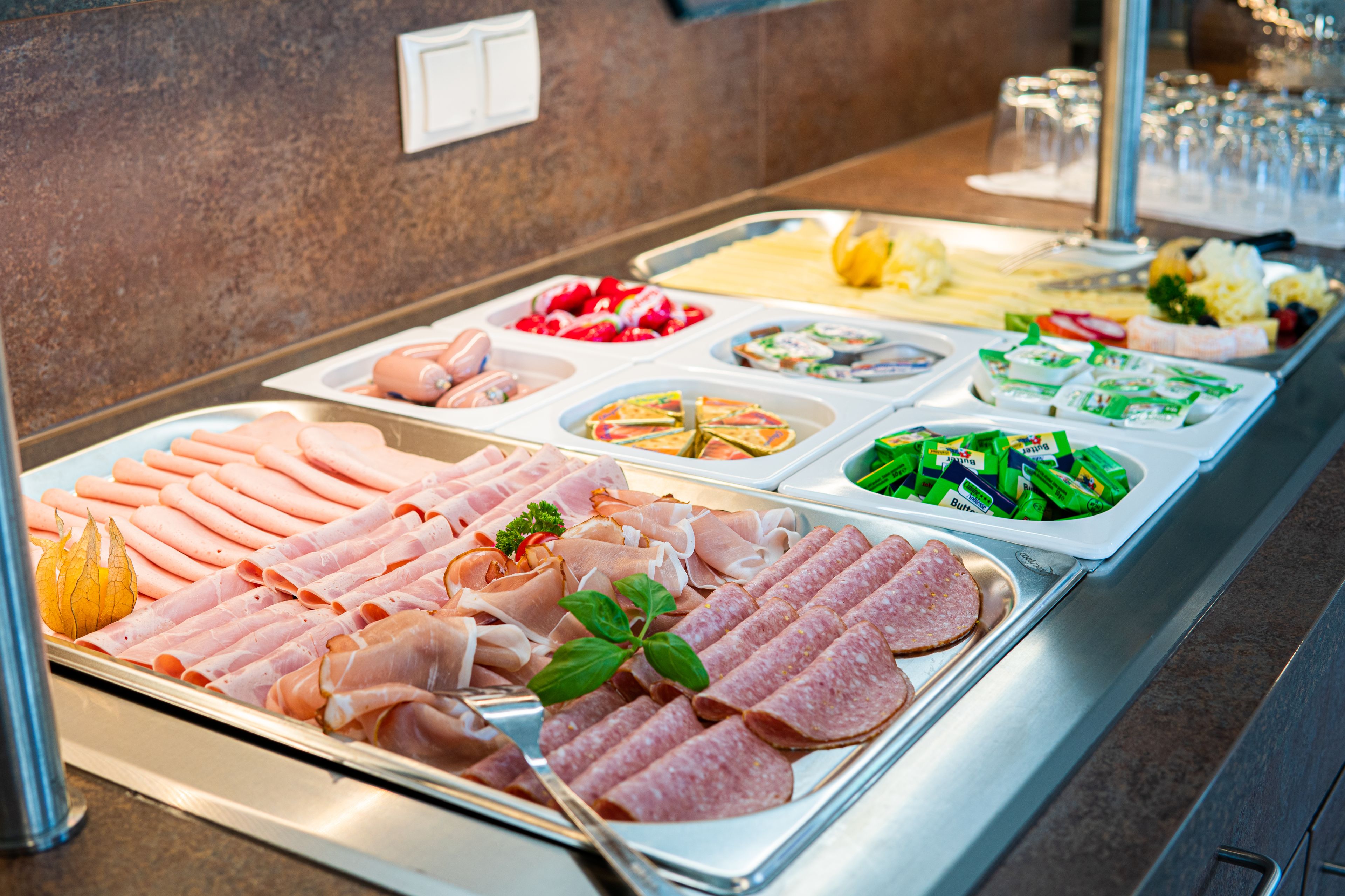 A buffet with various food options including meats, salads, and cheeses.