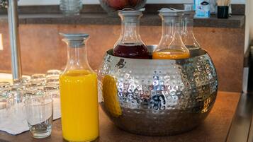 A kitchen counter with three glass bottles and a metal pitcher filled with various liquids.