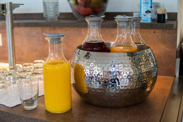 Una encimera de cocina con tres botellas de vidrio y una jarra de metal llena de diferentes líquidos.