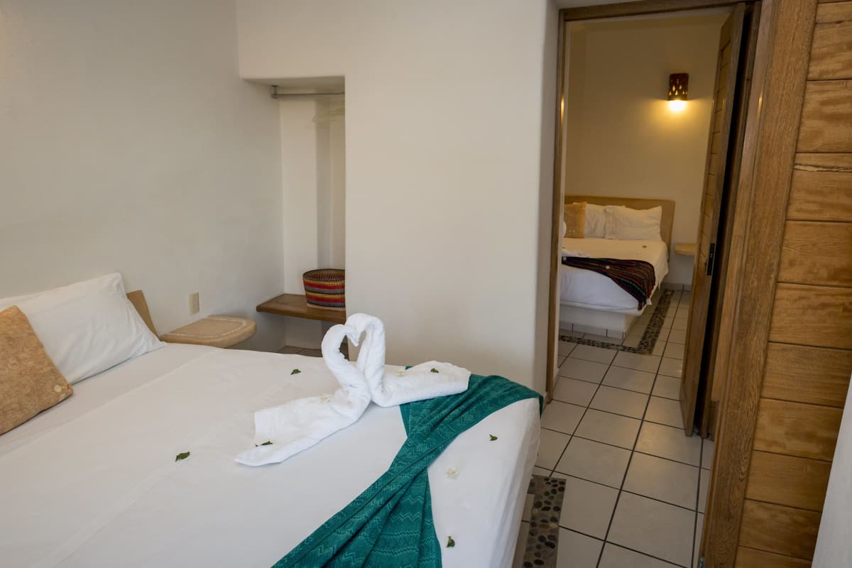 A hotel room with a bed, a small table, a basket, and a mirror.