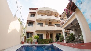 A multi-story building with a swimming pool in the foreground, balconies, and potted plants. - Canto del Mar Hotel & Villas (Zihuatanejo)