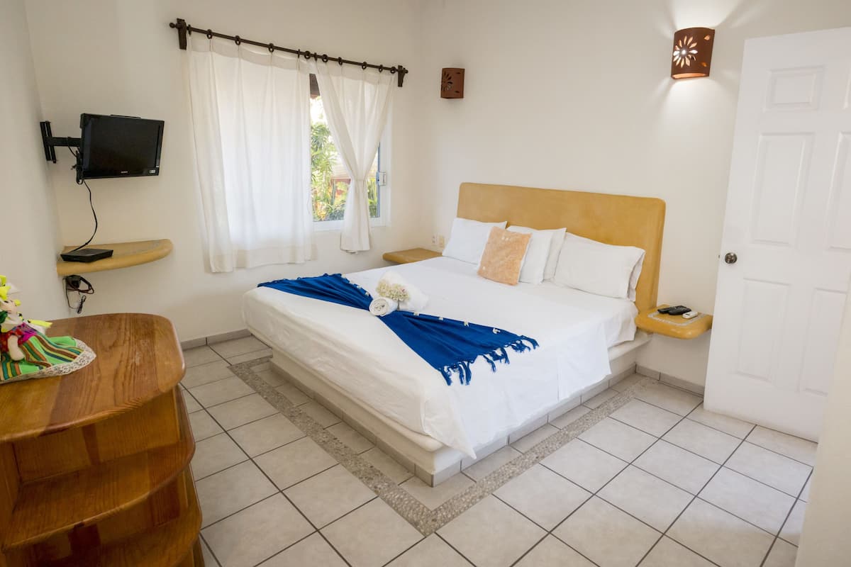 A hotel room with a bed, a desk, a TV, and a door.