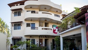 A multi-story building with balconies, a swimming pool, and potted plants. - Canto del Mar Hotel & Villas (Zihuatanejo)