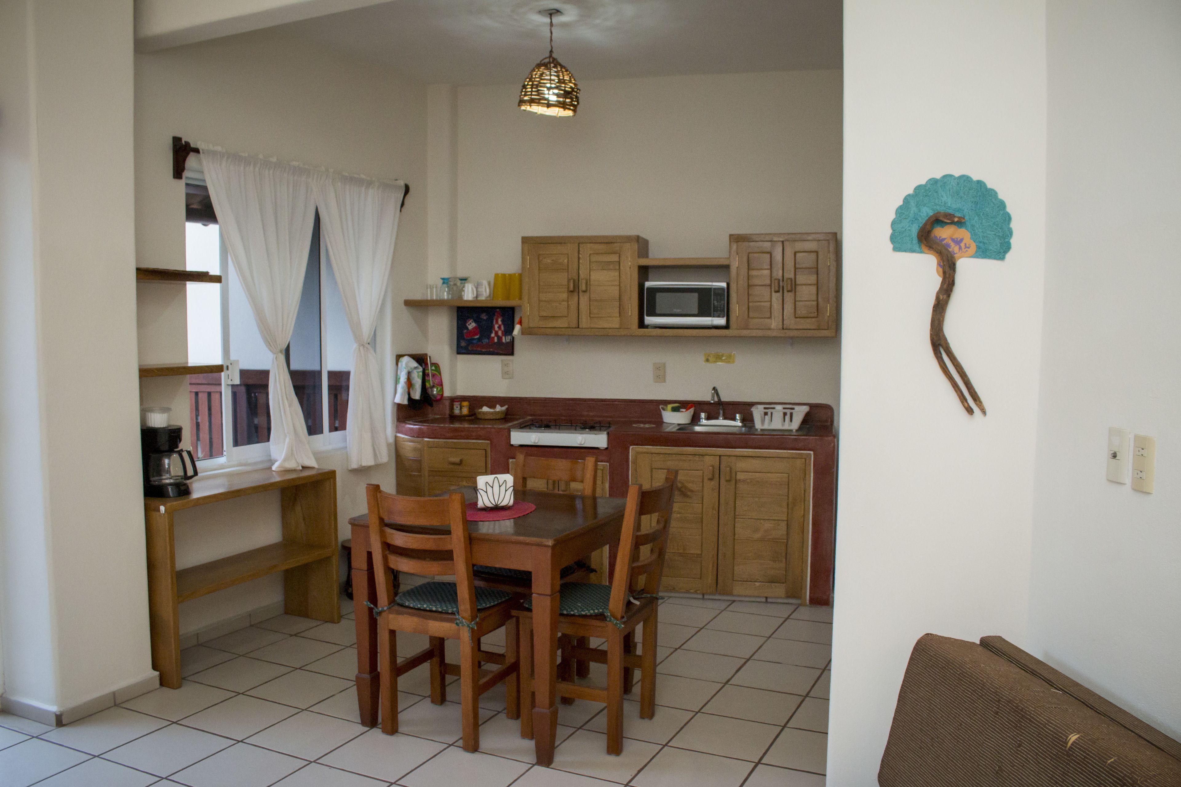 Una cocina compacta con armarios de madera, un microondas y una mesa de comedor con sillas.