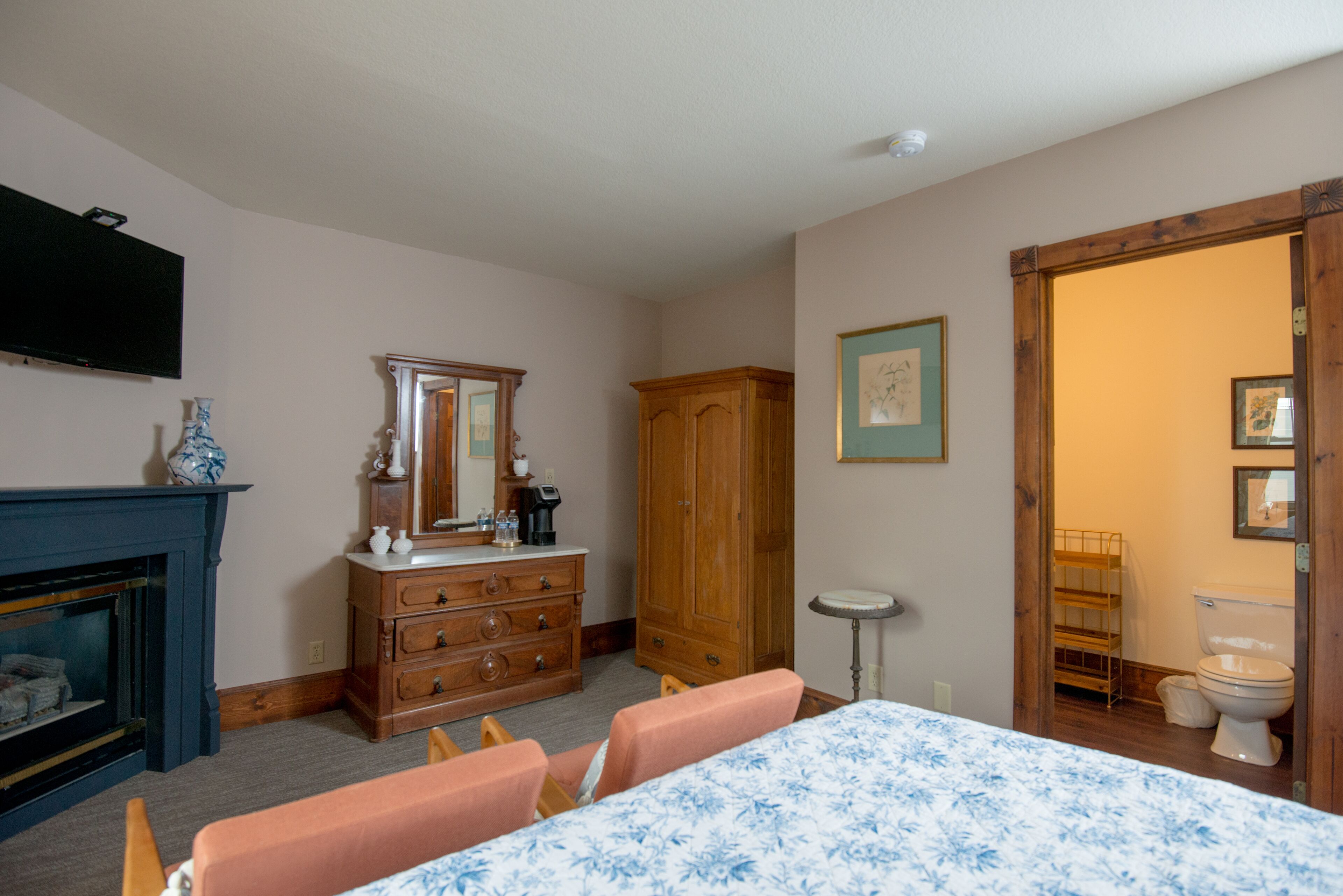 A room with a fireplace, wooden dresser, mirror, and a table with chairs.