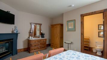 A room with a fireplace, wooden dresser, mirror, and a table with chairs.