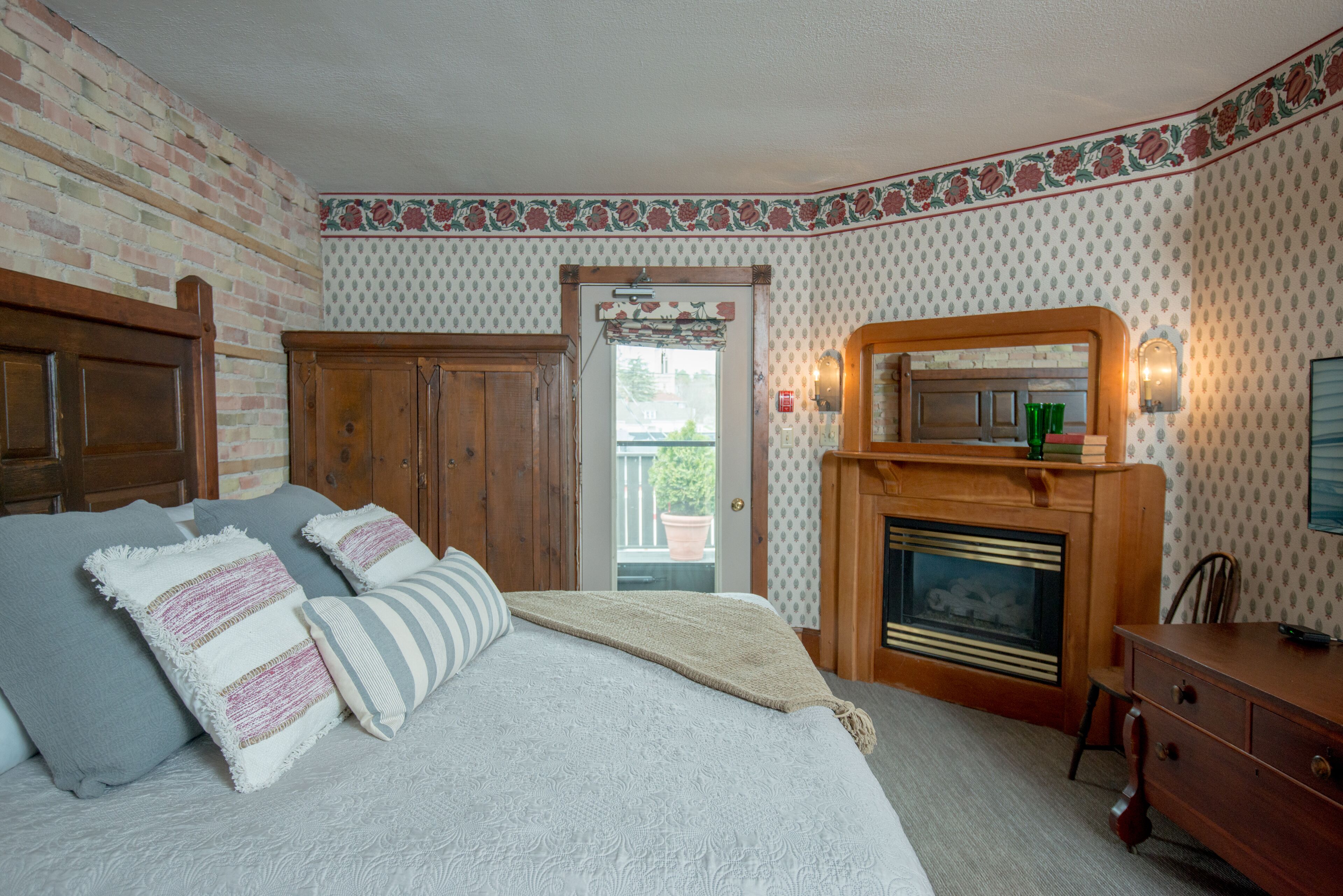 A bedroom with a bed, wooden wardrobe, and a fireplace.
