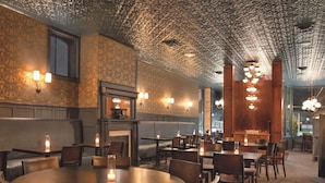 Un restaurant avec des tables rondes et des banquettes, un mur orné de motifs et un plafond à texture.
