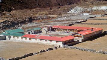 Un edificio de techo rojo y paredes de piedra, rodeado por un paisaje rocoso.