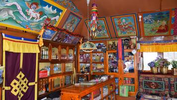 Una habitació amb decoració tradicional, incloent un mural colorit, un ornament penjant i un armari de fusta amb portes de vidre.