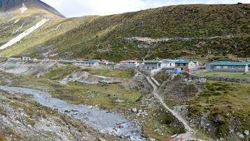 A mountainous area with several buildings, a stream, and a clear sky.