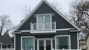 A two-story house with a dark exterior, white railings, and a front porch.