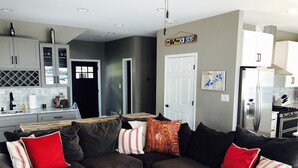 A modern living room with a dark grey sectional sofa, red and white striped pillows, and a wooden coffee table.