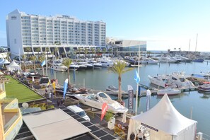 Un port de plaisance où sont amarrés de nombreux bateaux, un hôtel en arrière-plan et une tente abritant un centre nautique.