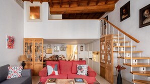 Ein geräumiger Wohnbereich mit einem roten Sofa, einem grauen Couche und einer Holztreppe.