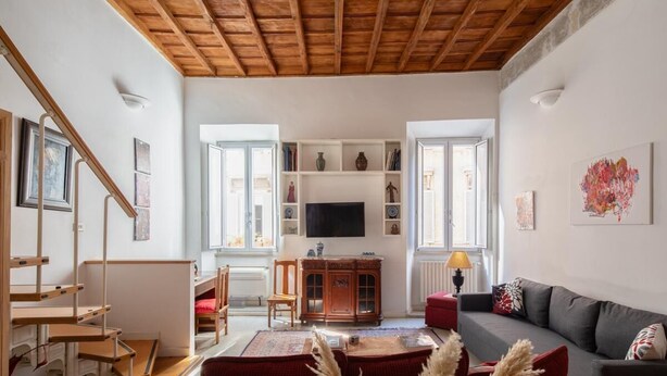 Ein Wohnzimmer mit Holzboden, einer Couch, einem Fernseher und einer Treppe.