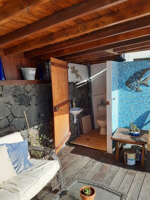 A wooden deck with a stone wall, a rustic bathroom with a blue mosaic fish, and a small table with plants. - Extremely Private Villa, Heated Pool & Jacuzzi, Pool Wet Bar, Great Views. (Las Coloradas)
