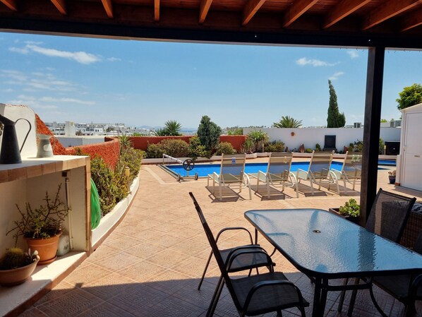 A rooftop pool area with lounge chairs and a table, surrounded by potted plants and a view of the cityscape. - Extremely Private Villa, Heated Pool & Jacuzzi, Pool Wet Bar, Great Views. (Las Coloradas)