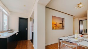 A modern kitchen with a dining area, wooden flooring, and a painting of a sunset bridge on the wall. - RENT4REST LISBON FAMILY & FRIENDS APARTMENT IN ROMA AVENUE (Lisboa ciudad)
