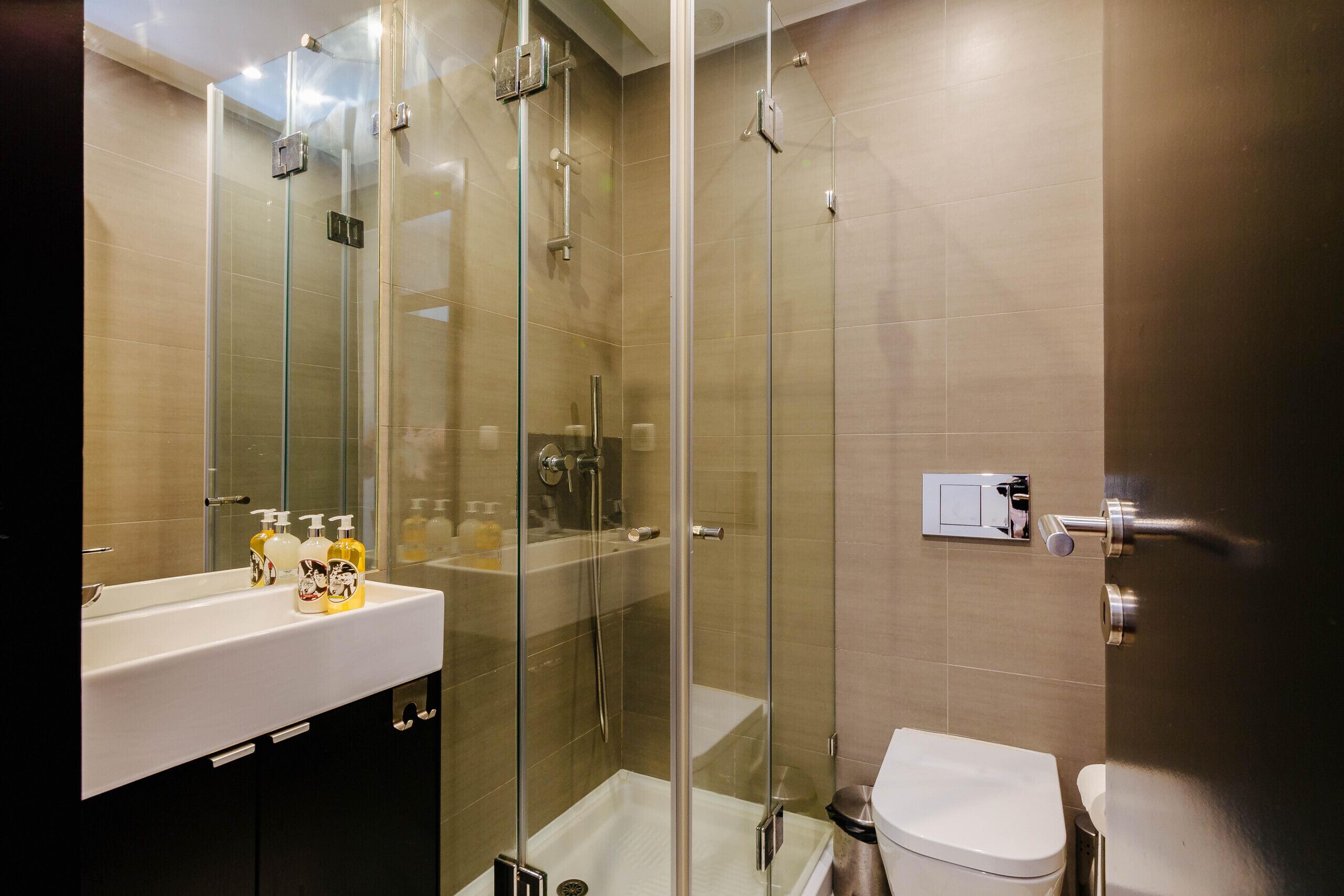 Un bagno moderno con doccia vetrata, lavabo bianco con articoli da toilette e WC.