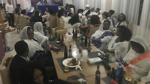 A room with round tables, some with food and drinks, and a stage with a backdrop in the background. - Gondar Plaza Hotel (Gondar)