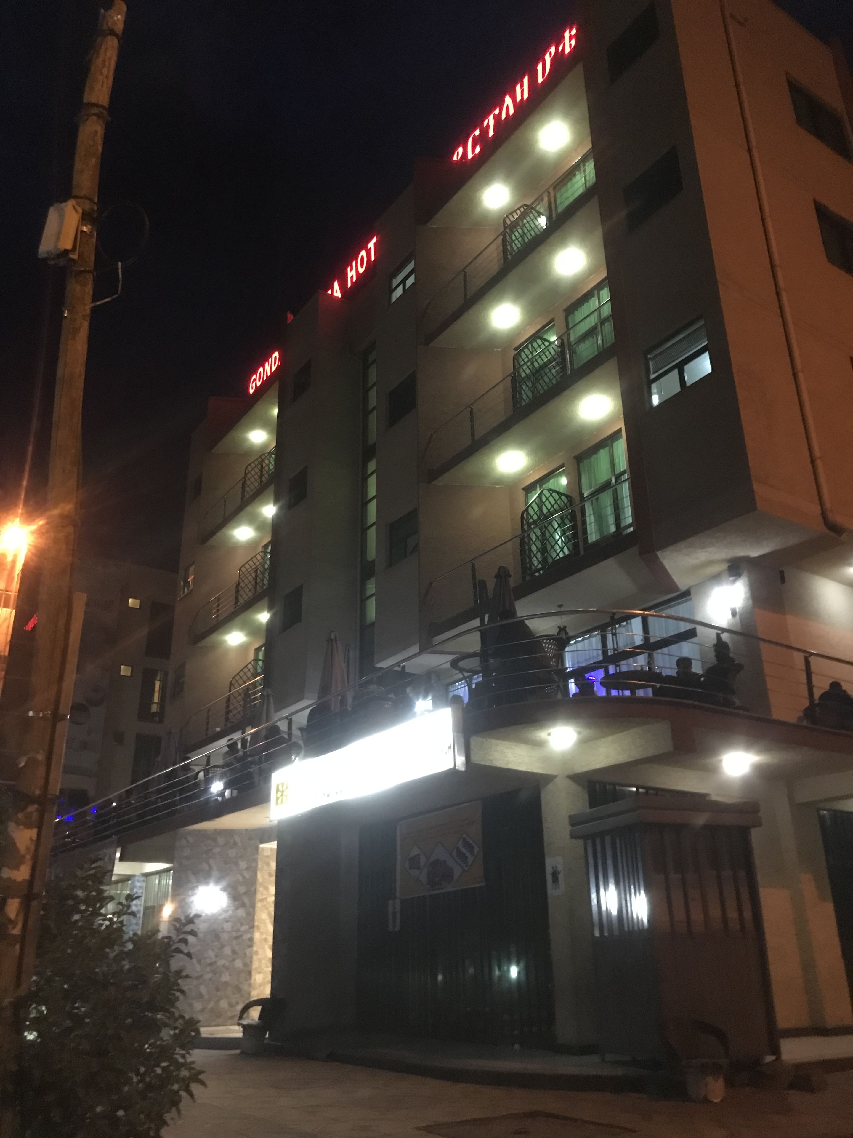Un hotel de varios pisos con señalización iluminada, balcones y una entrada bien iluminada.