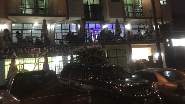 A multi-story hotel with illuminated signage, outdoor seating, and a visible parking area. - Gondar Plaza Hotel (Gondar)