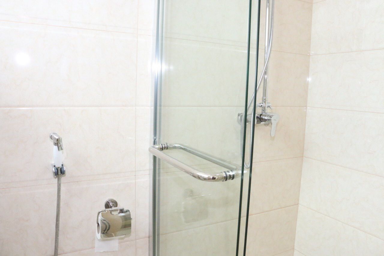 Ducha con cerramiento de vidrio, grifería de cromo y repisa de vidrio.