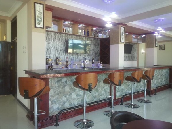 A bar area with a marble countertop, multiple bar stools, and a variety of bottles.
