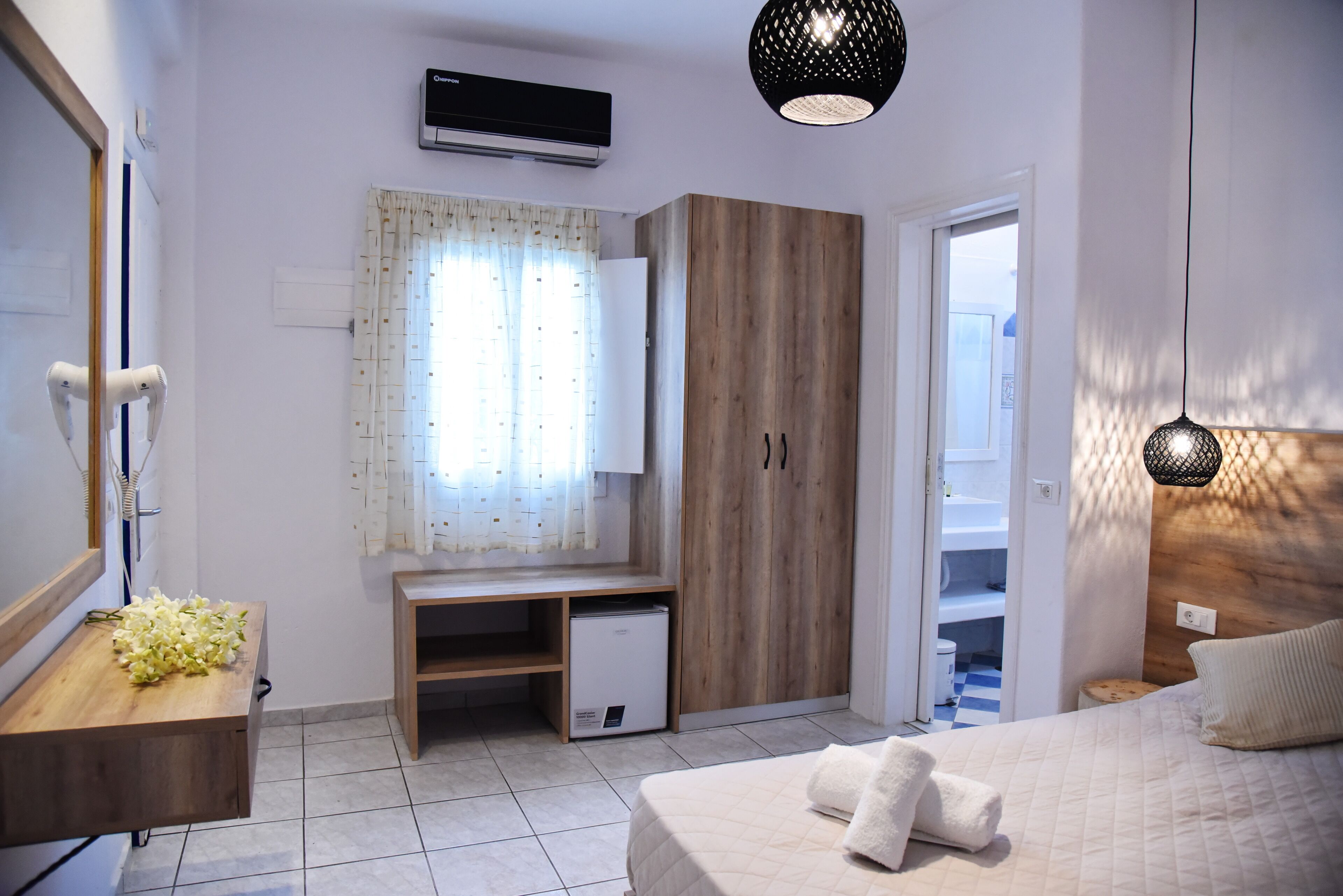 Ein Schlafzimmer mit einem Bett, einem Holztisch, einem Kleiderschrank und einem kleinen Kühlschrank.