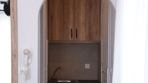 A narrow hallway with wooden cabinets, a sink, and a telephone. - Katerina View Mykonos (Mykonos)