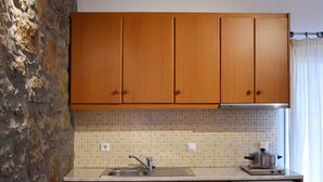 A kitchen with wooden cabinets, a tiled backsplash, a sink, a stove, and a refrigerator. - Katerina View Mykonos (Mykonos)