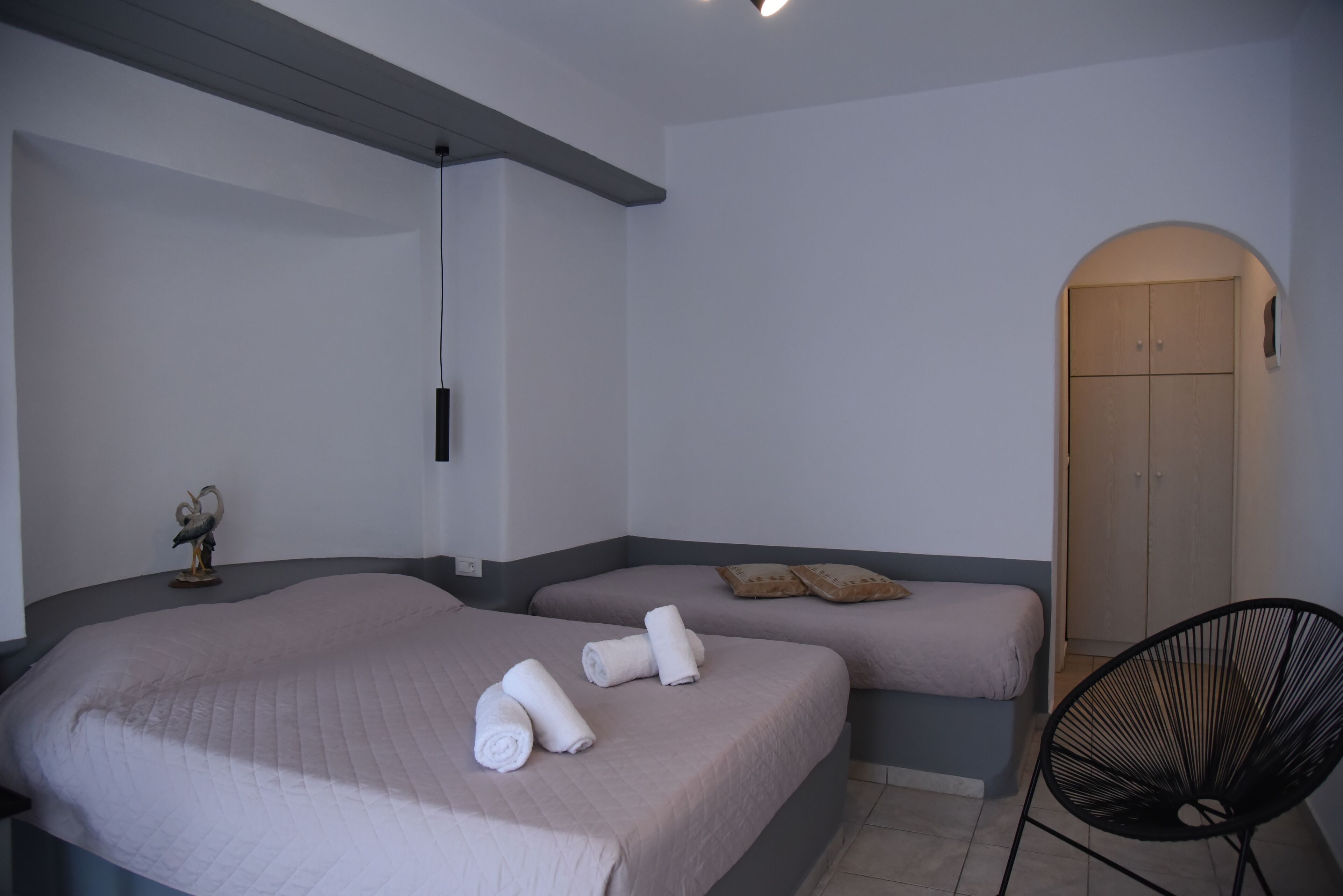 A hotel room with two beds, a chair, and a wooden door.