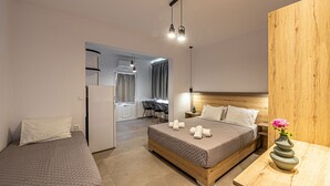 A modern hotel room with a large bed, a smaller bed, a wooden nightstand, and a desk with a chair. - Katerina View Mykonos (Mykonos)