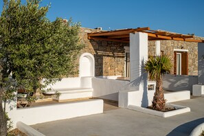 A stone building with white walls and a wooden pergola.