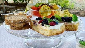 Un plateau de desserts avec divers fruits et une part de gâteau, le tout présenté sur un présentoir en verre.
