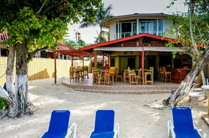 A beachside resort with a covered dining area, outdoor seating, and lounge chairs. - Xye   Resort (Negril)
