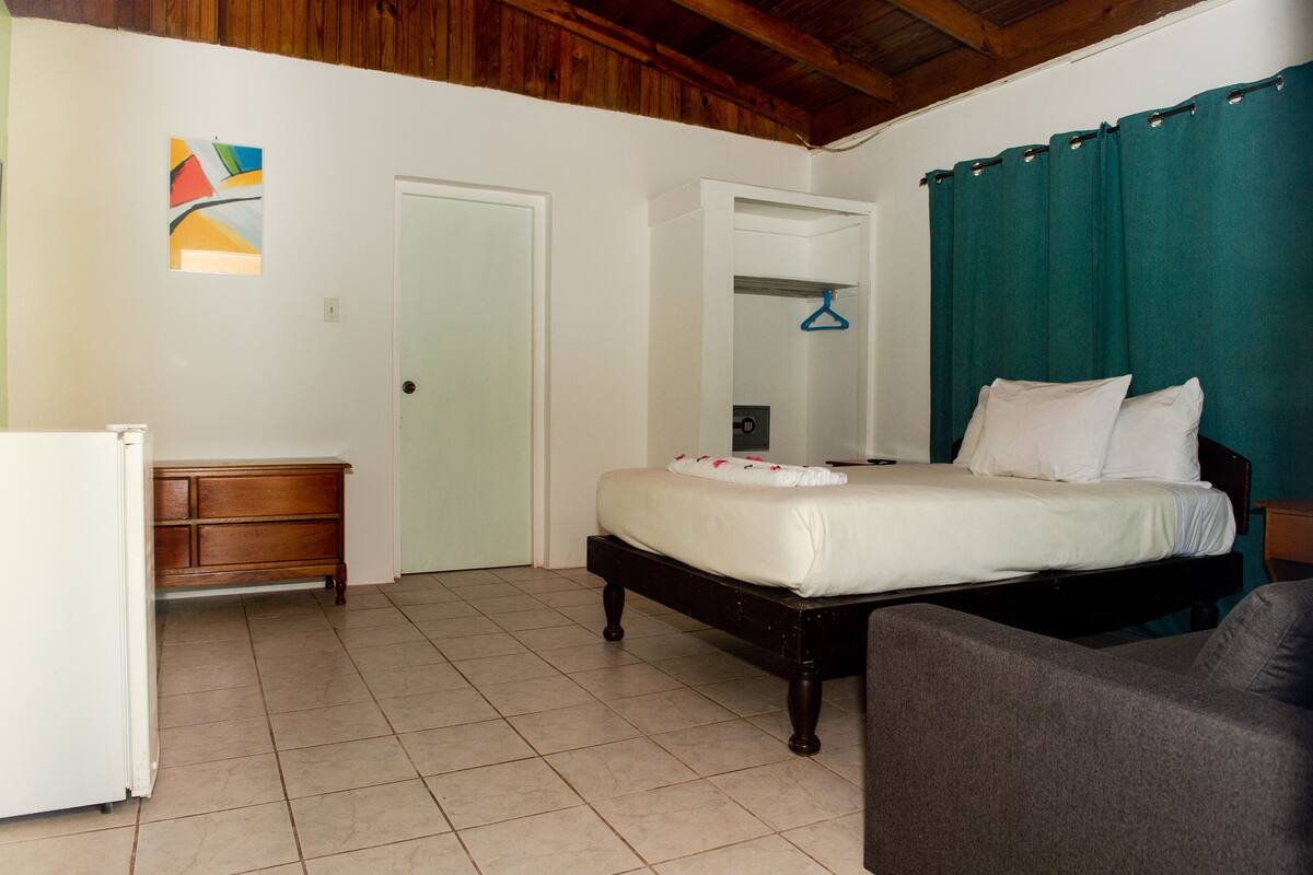 Un dormitorio con cama, cómoda, silla y puerta que da a otra habitación.