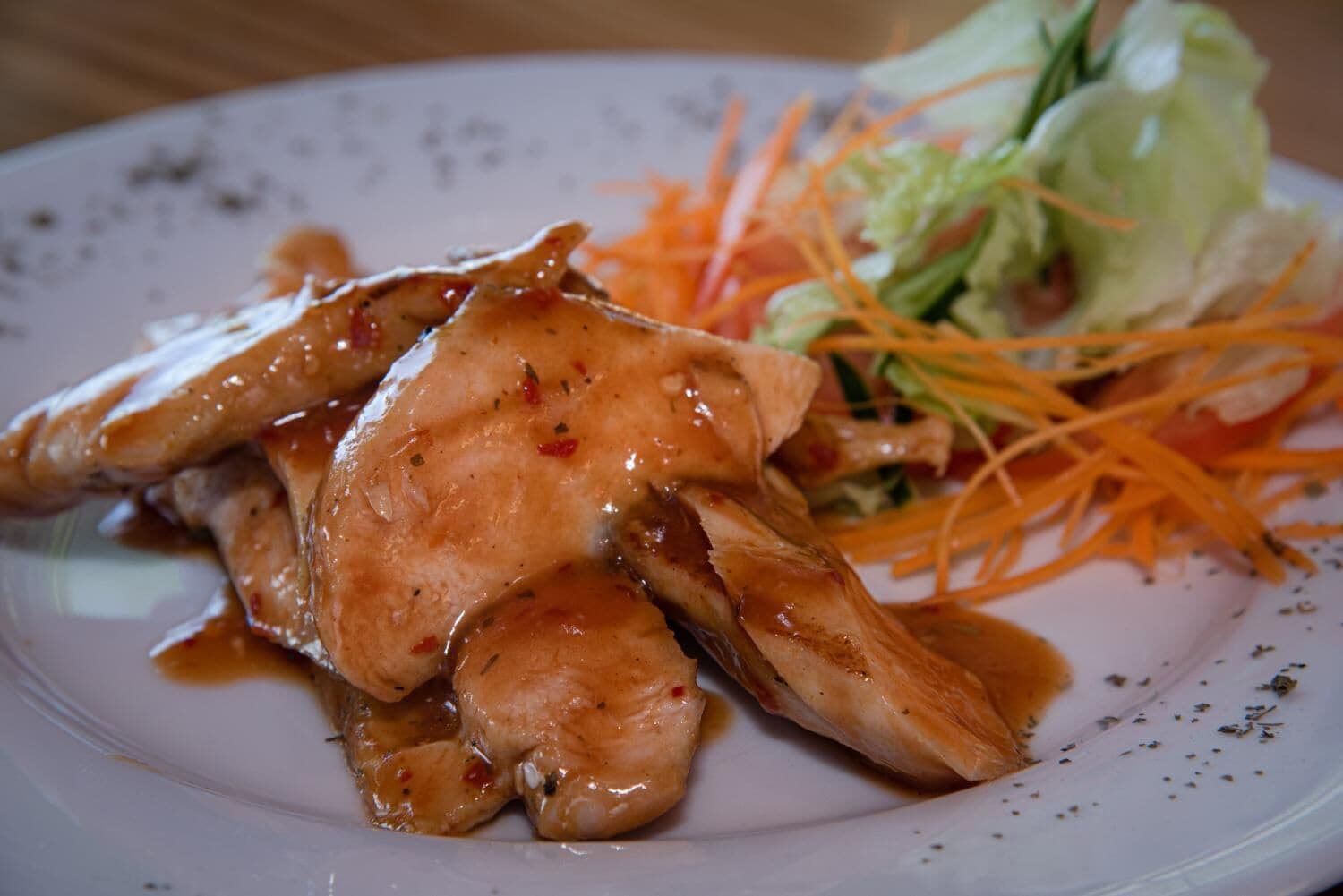En tallerken med grillerede kyllingevinger, en salat og en cremet sauce.