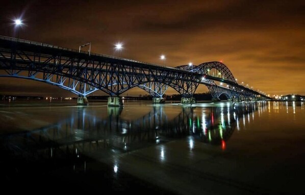 Vista nocturna de un gran puente de acero con su reflejo en el agua.