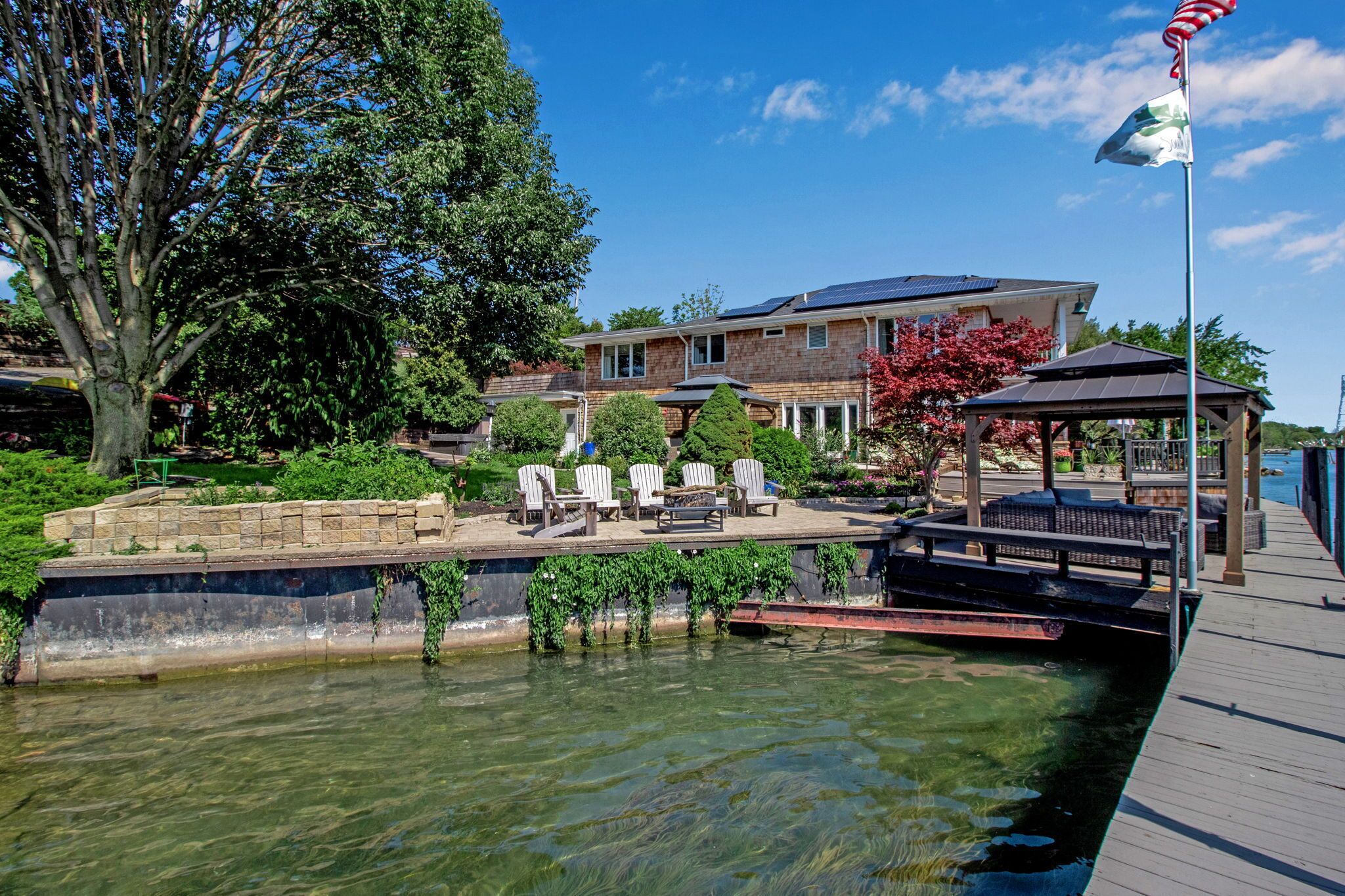 A waterfront property with a dock, lounge chairs, and a gazebo.