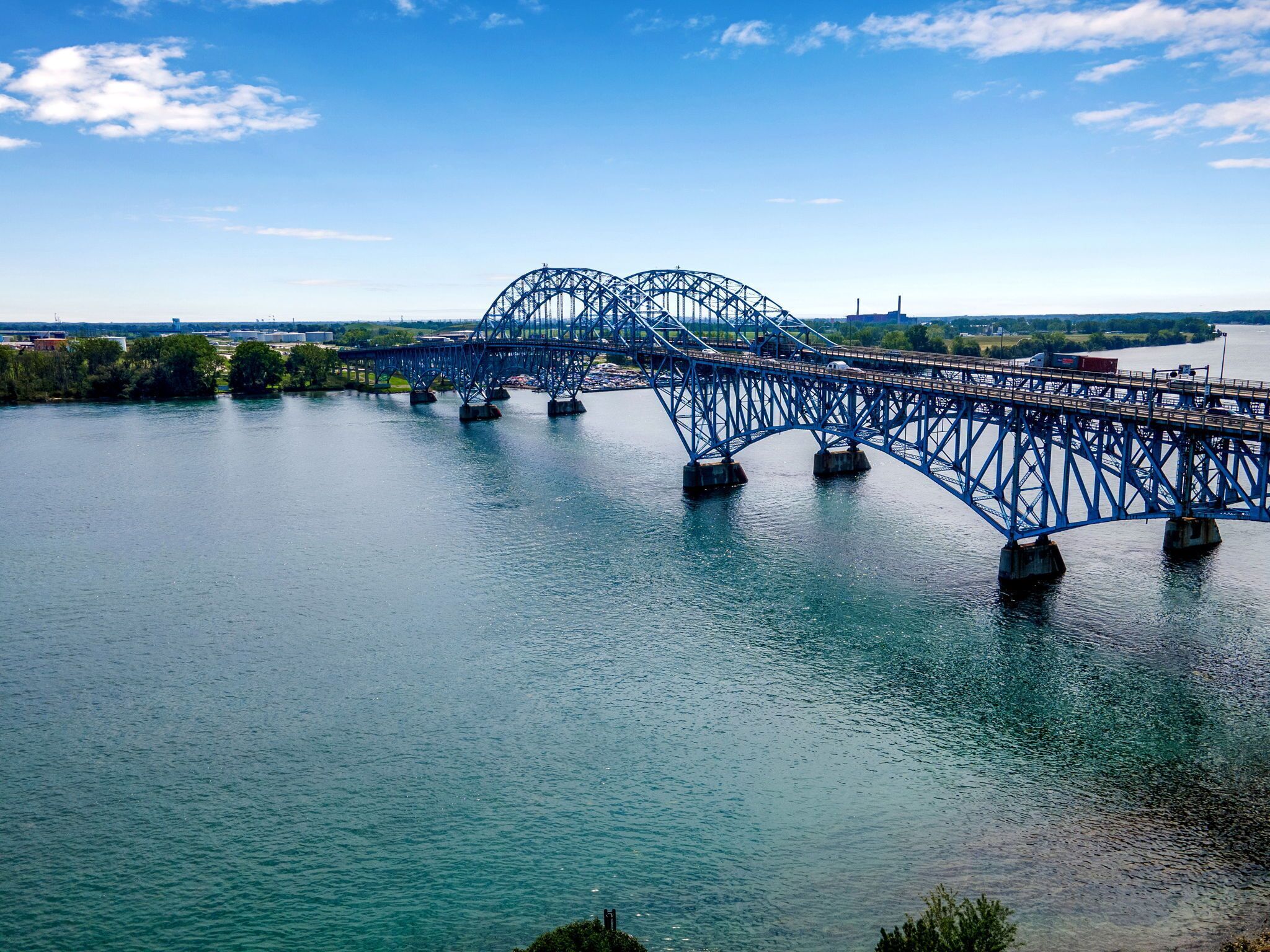 A large blue bridge spanning a river with calm water.