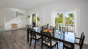 A spacious dining area with a large table, multiple chairs, and a staircase leading to an upper level. - Newly Updated Beach House @ Famous French Leave Bch, Htd Pool, Paddle Boards (Governors Harbour)